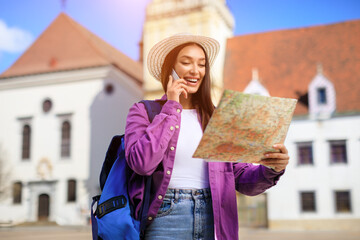 Happy tourist talking on phone with map