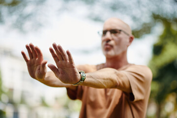 Mature man doing tai chi breathing exercise outdoors
