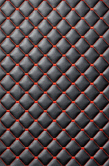 Black upholstery leather is stitched with red quilted threads. - 786572473