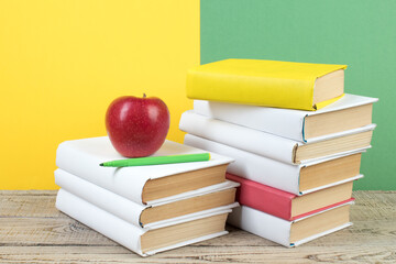 Books stacking. Books on wooden table and green, yellow background. Back to school. Copy space for...