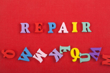 REPAIR word on red background composed from colorful abc alphabet block wooden letters, copy space for ad text. Learning english concept.