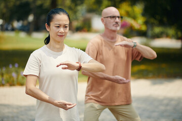 Mature people doing arm circle exercise when working out outdoors