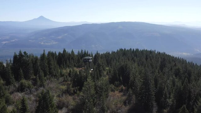 A mountain range with a small cabin in the middle. The cabin is surrounded by trees and the view is breathtaking
