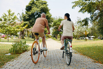 Active man and woman riding bicycles in city park