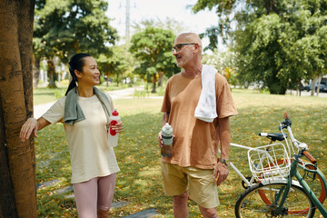Smiling mature couple discussing bicycle ride and drinking water - 786574231