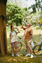 Thirsty mature couple drinking fresh water after bicycle ride - 786574835