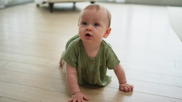 Happy baby. Cute little newborn girl with smiling face crawling on floor in bedroom. Infant baby resting playing in living room indoor at home. Motherhood happy child childcare concept