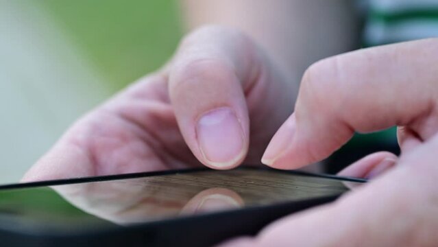 Closeup of female hands text messaging on smartphone on public park bench