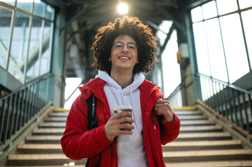 Curly-haired young guy in red jacket at the railway station
