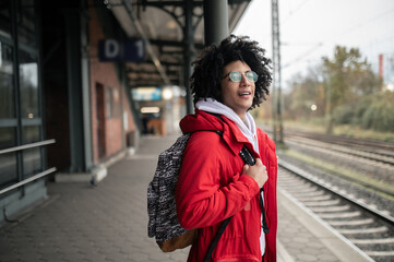 Guy in red jacket and with backpack waiting for the train at the platform