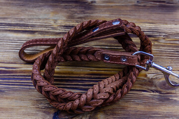 Brown leather dog leash on a wooden background