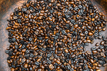 Heap of the roasted coffee beans in wooden plate
