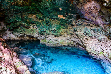 Stalactites and stalagmites in a Kuza cave at Zanzibar, Tanzania. Natural pool with crystal clear water - obrazy, fototapety, plakaty