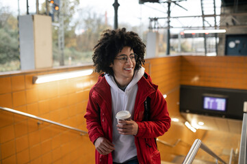 Traveler in red jacket having coffee and waiting for the train