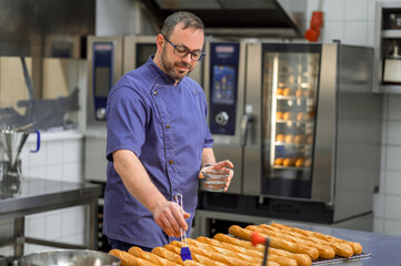 Man baker in uniform baking baguettes with bread shelves on background