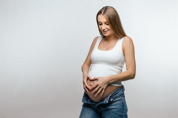 Fair-haired young pregnant woman holding her big belly
