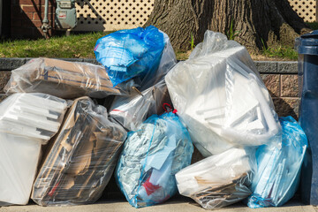 recycling pick up day: seperated materials in see through plastic bags await collection on a city...