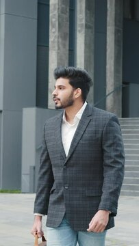 Vertical Screen: Shot of moving around businessman stand on street in downtown near elite office. Portrait Handsome muslim businessman in stylish formal wear walking outdoors