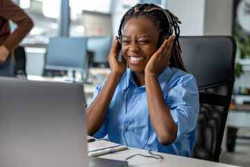 Attractive dark skinned woman in headset working on laptop