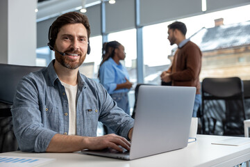 Smiling man working in call center on phone with headset