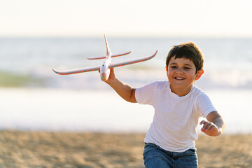 Smiling child proudly displaying a toy plane on the seashore