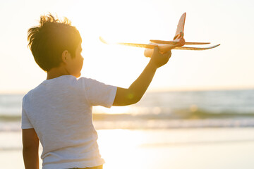 Boy with a toy plane in the glow of the sunset