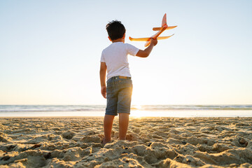 Child in sunset light launching a toy airplane.