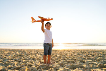 A smiling boy proudly holds up a toy airplane.