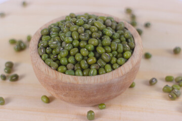 Green raw mung beans in wooden bowl on wooden and white background