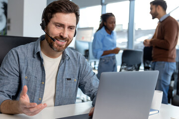 Professional call center operator man in headset working on laptop