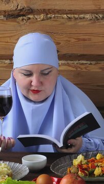 A Jewish woman in a blue veil at the Pesach Seder table reads kiddush with a glass of wine