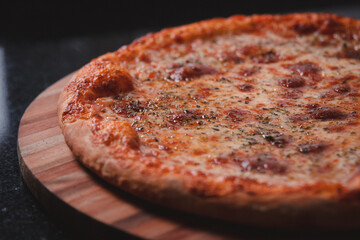 Detail view of a mozzarella pizza on a black granite table.