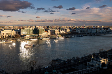Sun reflecting from windows in Danube river during golden sunset over Budapest city, Hungary