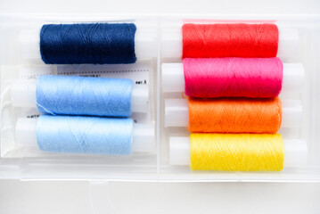 Multicolored skeins of thread in the set. The threads are in a plastic box.
