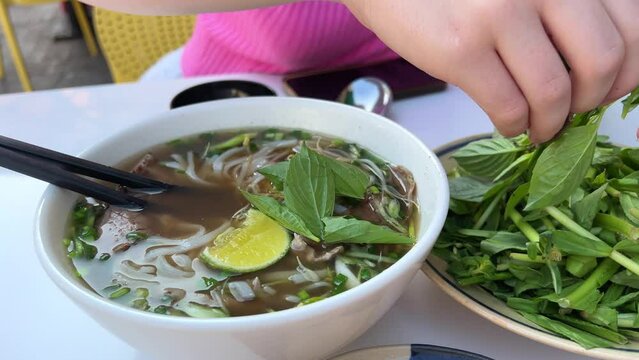  Female hands hold bowl with Asian traditional soup. Beef pho bo with eggs. Cardboard containers for food, mock up