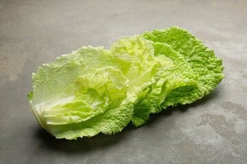 Fresh Chinese cabbage leaves on gray textured table, closeup