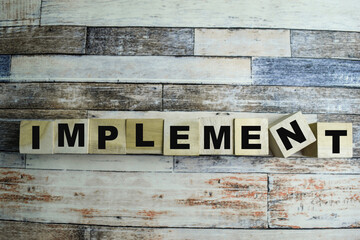 Concept of The wooden Cubes with the word Implement on wooden background.