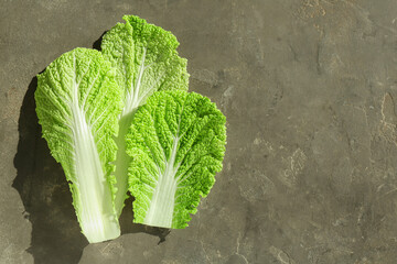 Fresh Chinese cabbage leaves on gray textured table, top view. Space for text