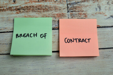 Concept of Breach of Contract write on sticky notes isolated on Wooden Table.
