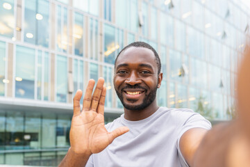 African American man with smartphone having video call on street in city. Guy blogger streaming...