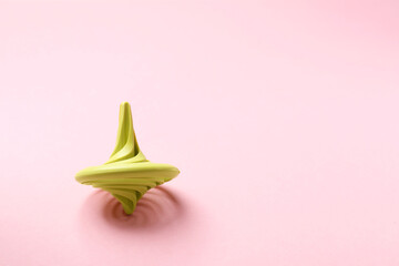 One green spinning top on pink background, space for text