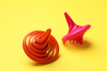 Red and pink spinning tops on yellow background, closeup