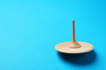 One wooden spinning top on light blue background, space for text