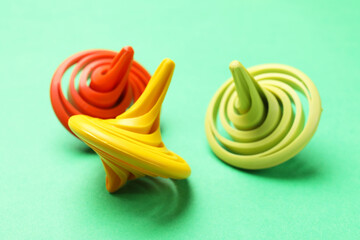Many colorful spinning tops on green background, closeup