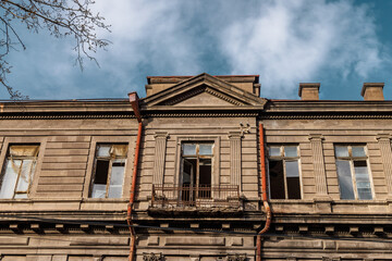 Historical building facade with external pipes and broken window panes in Armenia, Yerevan.