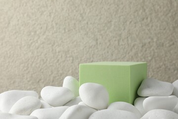 Presentation for product. Light green cube podium and white pebbles on blurred background. Space...
