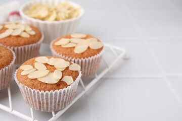 Muffins with fresh almond flakes on white tiled table, closeup. Space for text