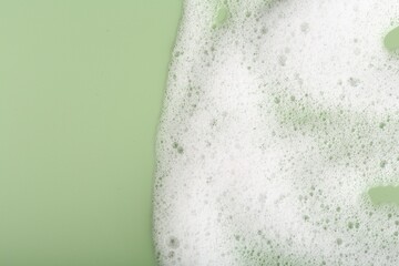 Obraz premium White fluffy foam on green background, top view. Space for text