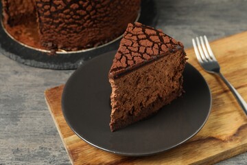Piece of delicious chocolate truffle cake on grey textured table, closeup