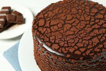 Delicious truffle cake and chocolate pieces on white table, closeup